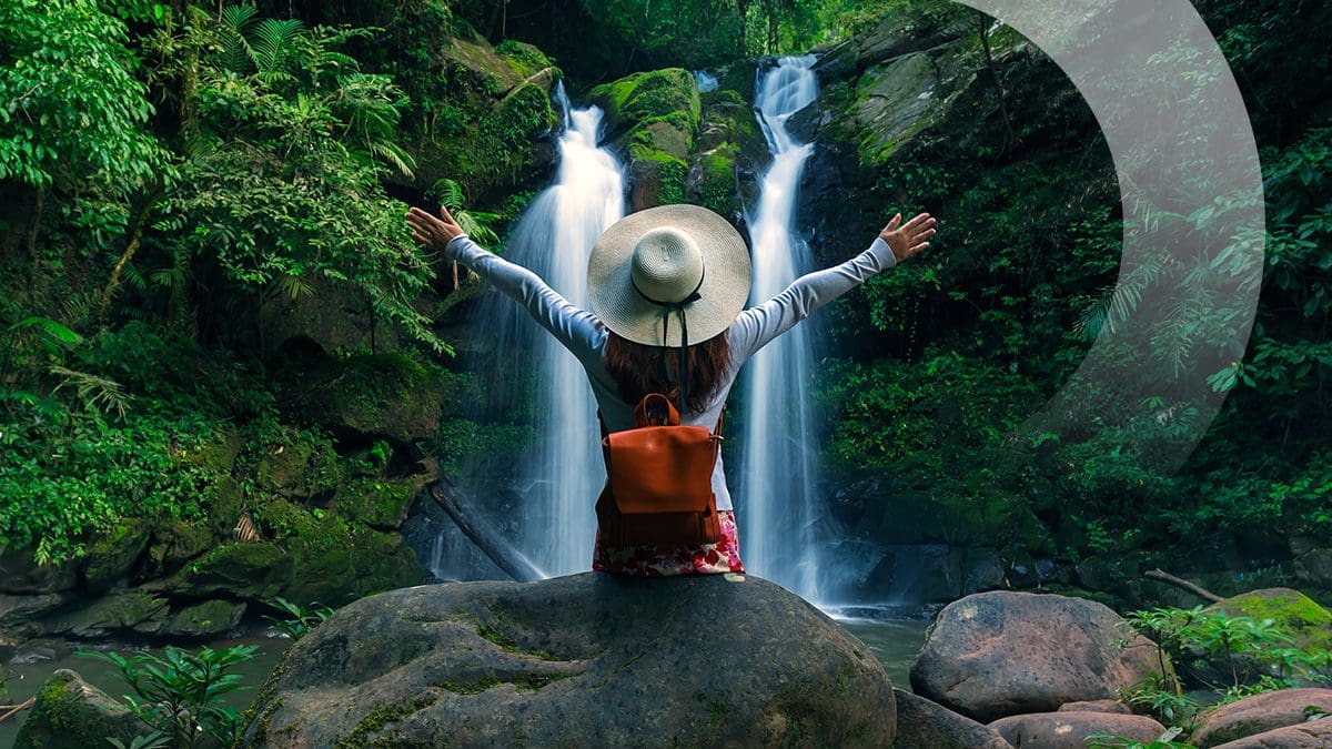 Female traveler benefiting from travel rewards enjoying a scenic waterfall