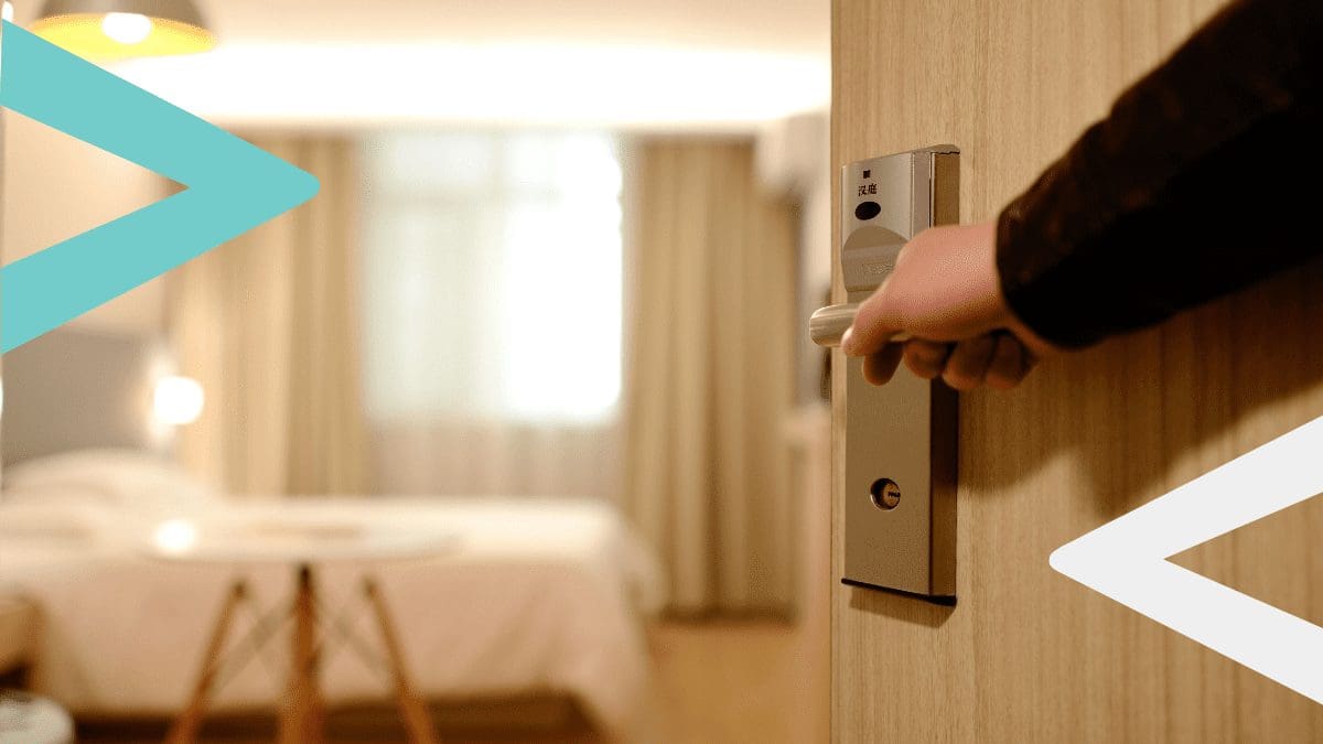 Hand opening a door of a hotel room booked on a hotel booking platform